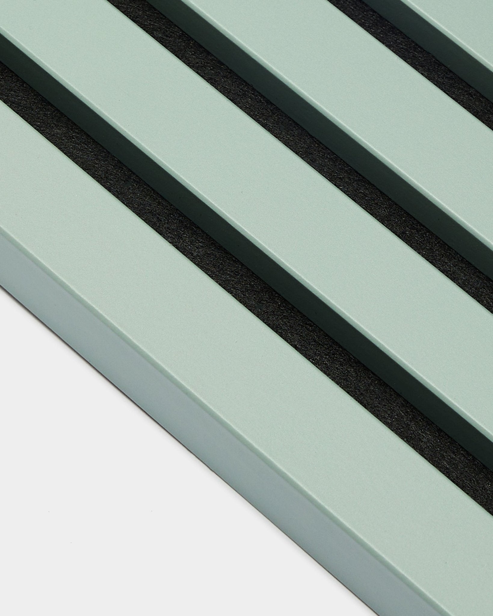 Close-up van drie parallelle pastelgroene End Lamella / Cloud latten van 2,2 cm breed, van WoodUpp, als onderdeel van een Akupanel Akoestisch paneel tegen een lichte achtergrond.